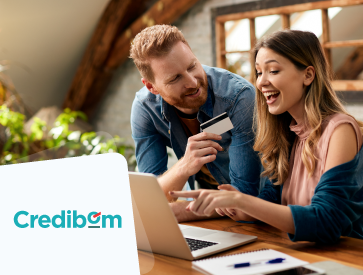 Couple sits at a table with a laptop and credit card. "Credibom" logo in the corner.